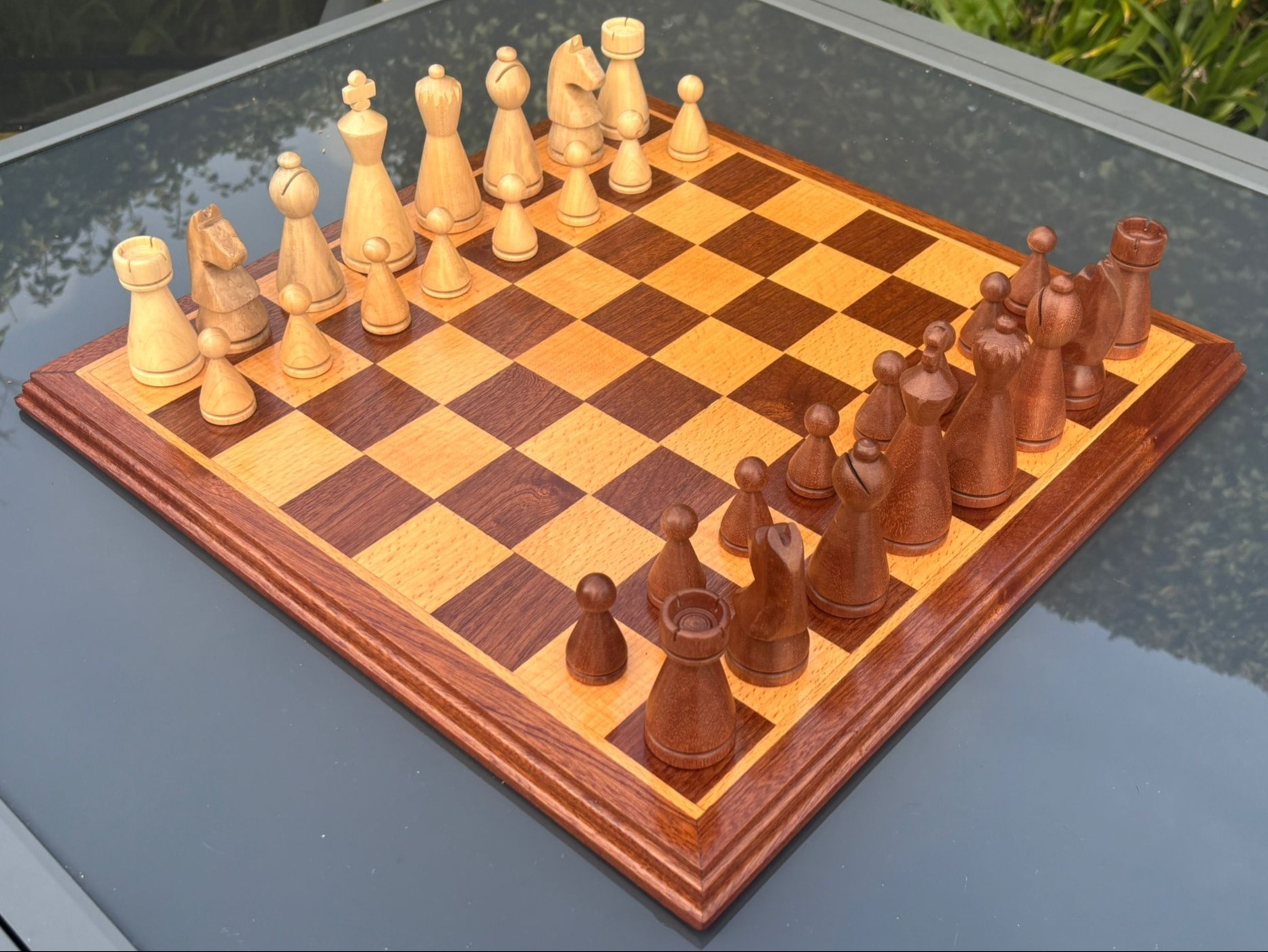Hand-carved wooden chess pieces arranged on a chessboard