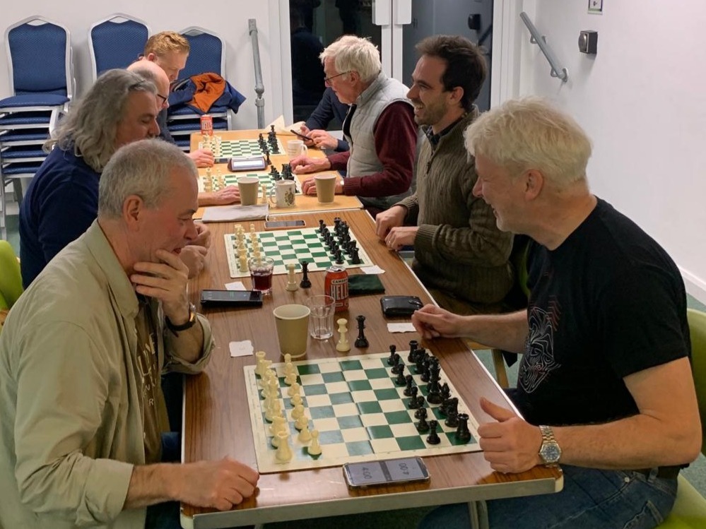 Chess club members and visitors seated at tables during a club night